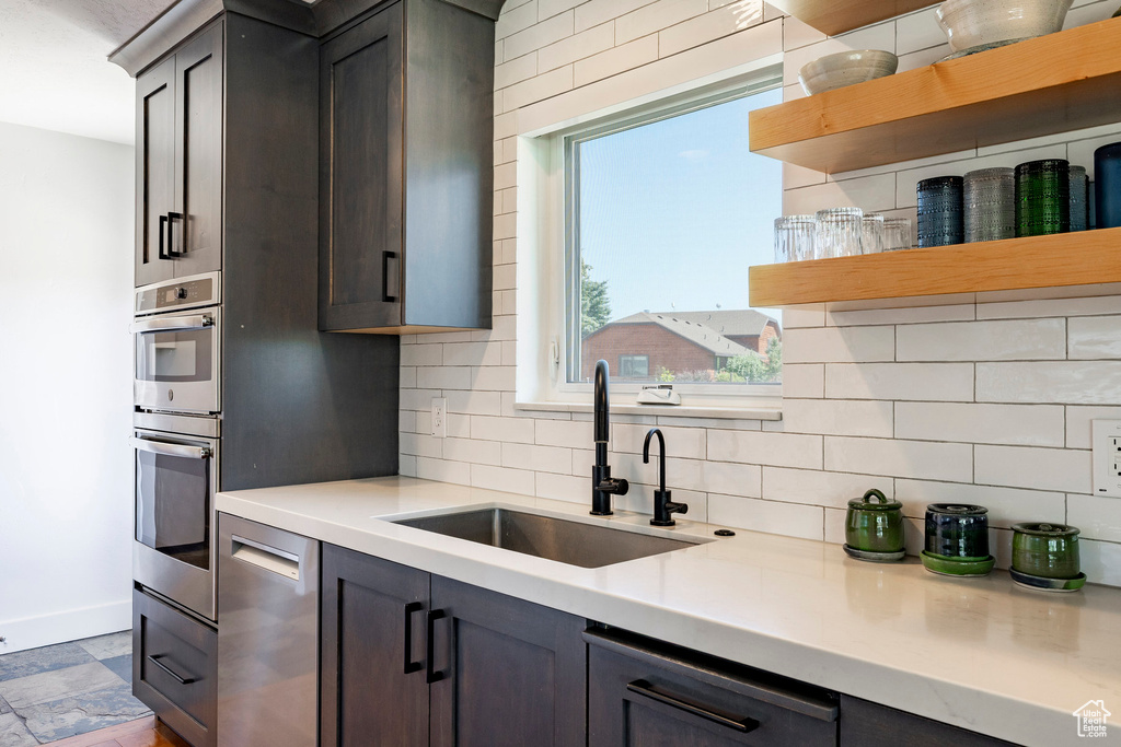 Kitchen featuring open shelves, backsplash, light countertops, and stainless steel appliances