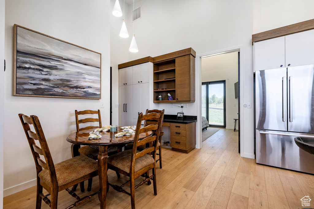 Dining room with a towering ceiling and light wood-style flooring