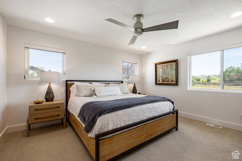 Bedroom featuring light colored carpet, multiple windows, recessed lighting, and a ceiling fan
