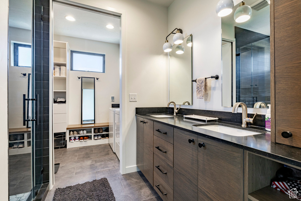 Bathroom with independent washer and dryer, plenty of natural light, double vanity, and a stall shower