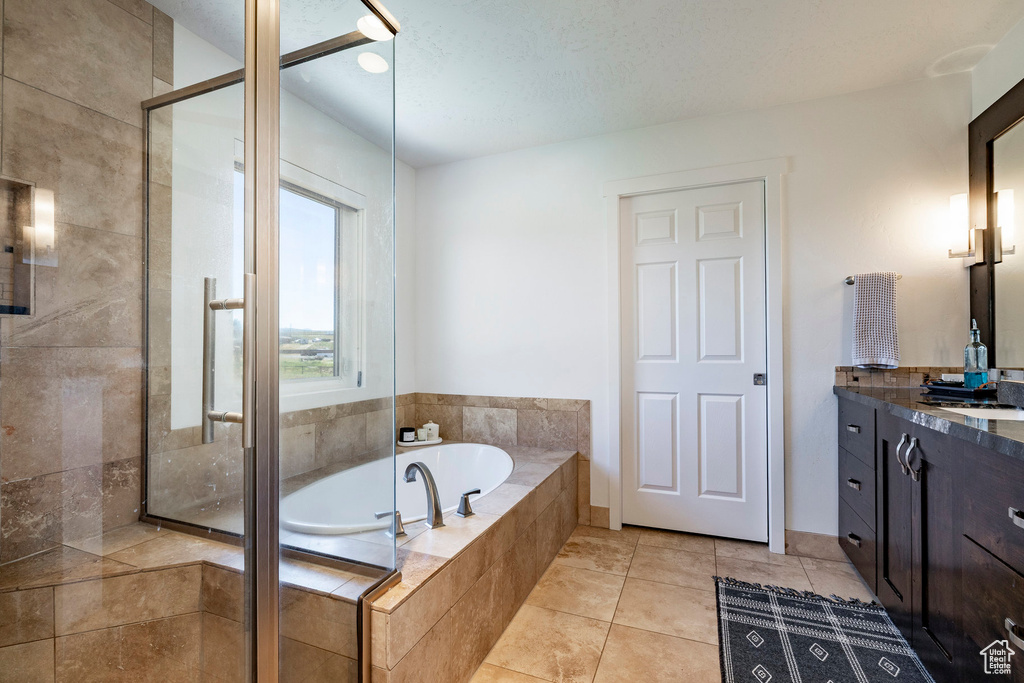 Bathroom featuring vanity, a garden tub, a shower stall, and tile patterned floors