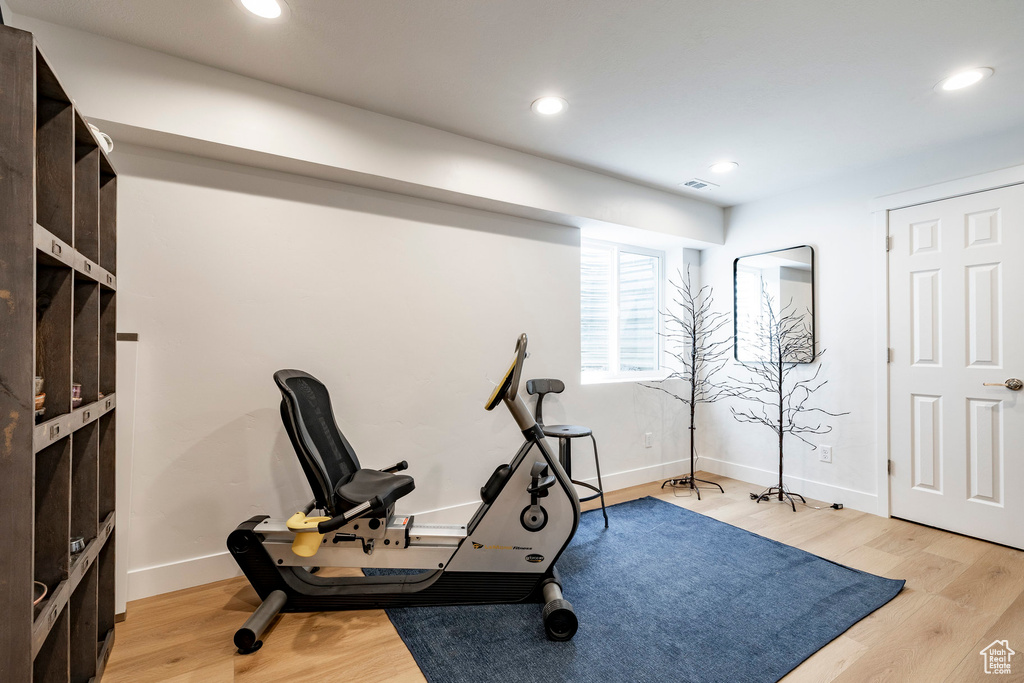 Workout area featuring light wood-type flooring and recessed lighting