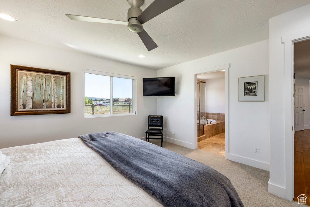 Bedroom with a textured ceiling, light carpet, recessed lighting, a ceiling fan, and ensuite bathroom