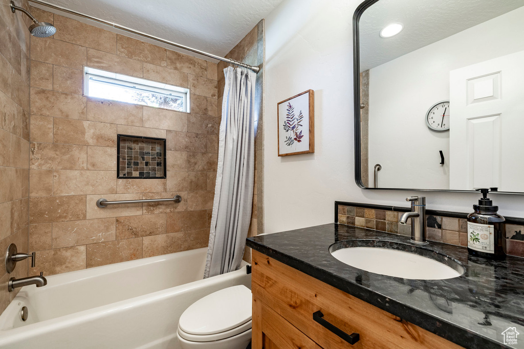 Bathroom featuring shower / bath combo with shower curtain, vanity, and a textured ceiling
