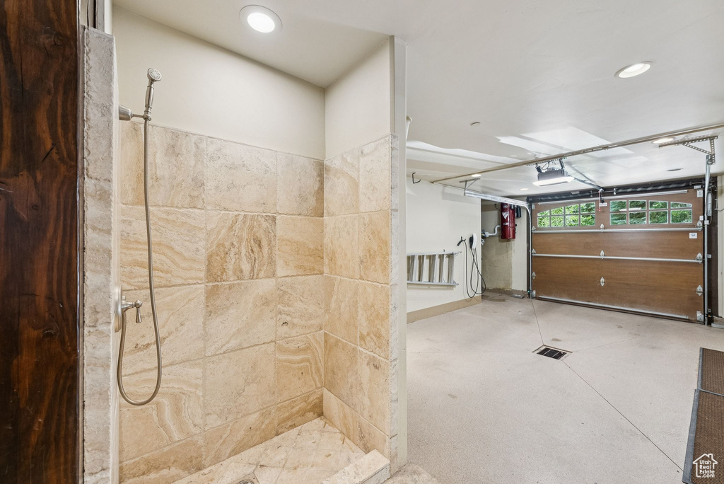 Bathroom featuring tiled shower, recessed lighting, and concrete floors