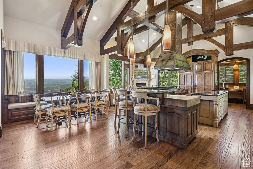 Interior space featuring a spacious island, beam ceiling, dark wood-style flooring, a breakfast bar area, and plenty of natural light