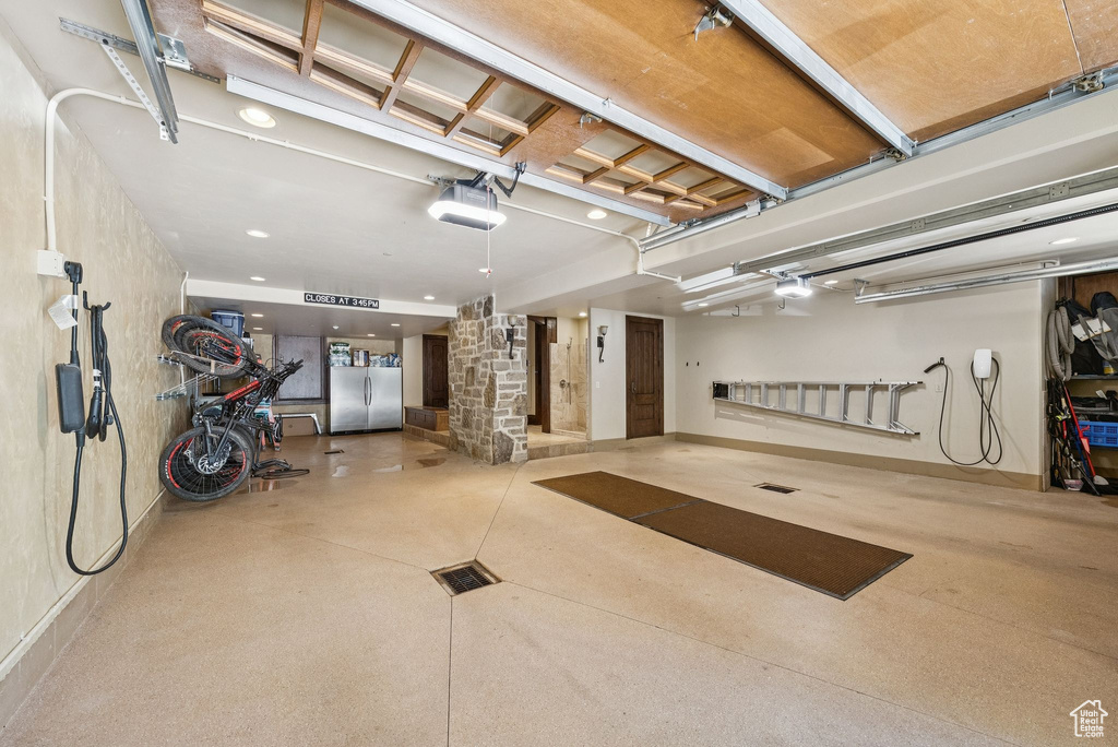 Garage featuring a garage door opener and freestanding refrigerator