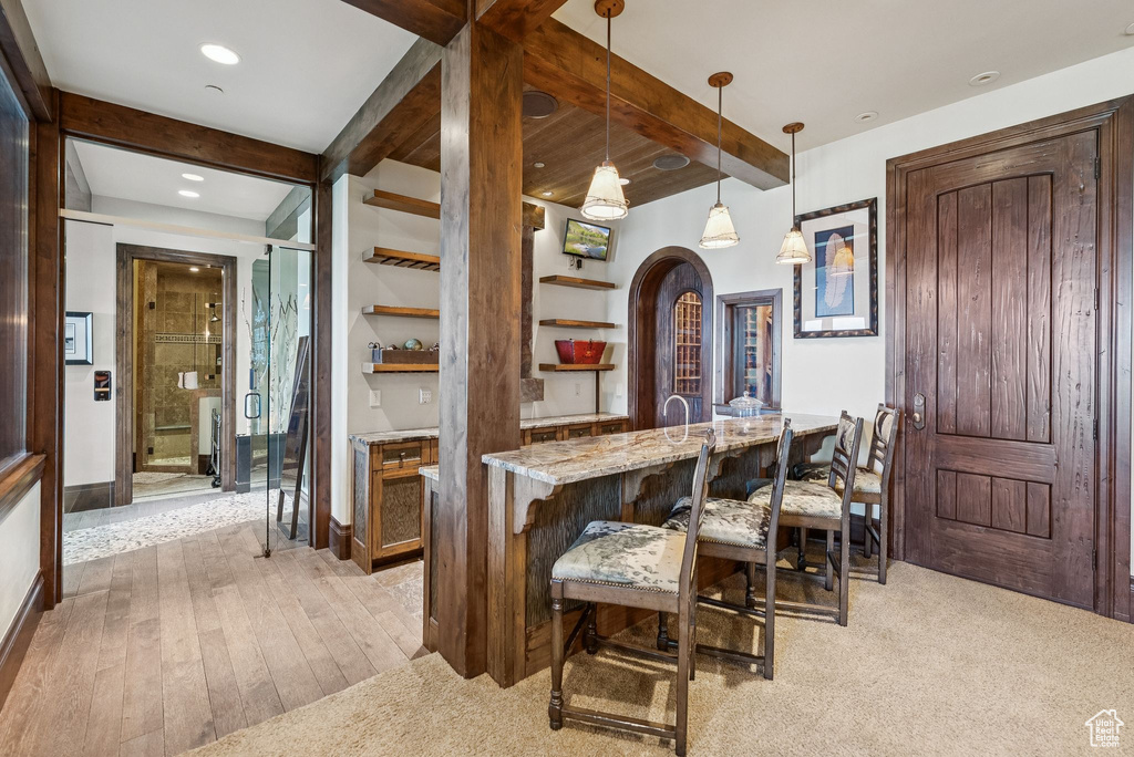 Dining room with beamed ceiling, bar, light wood-style flooring, arched walkways, and recessed lighting