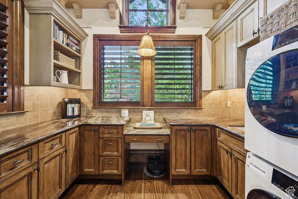 Kitchen with stacked washer and clothes dryer, dark stone counters, and tasteful backsplash