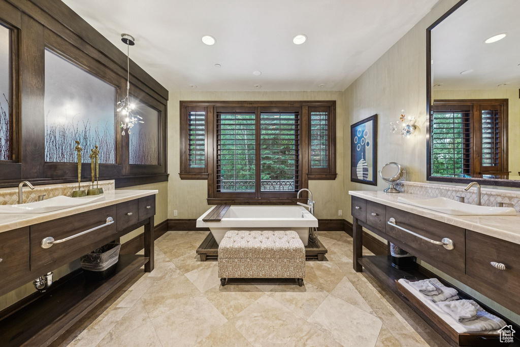 Bathroom featuring a freestanding tub, two vanities, and recessed lighting