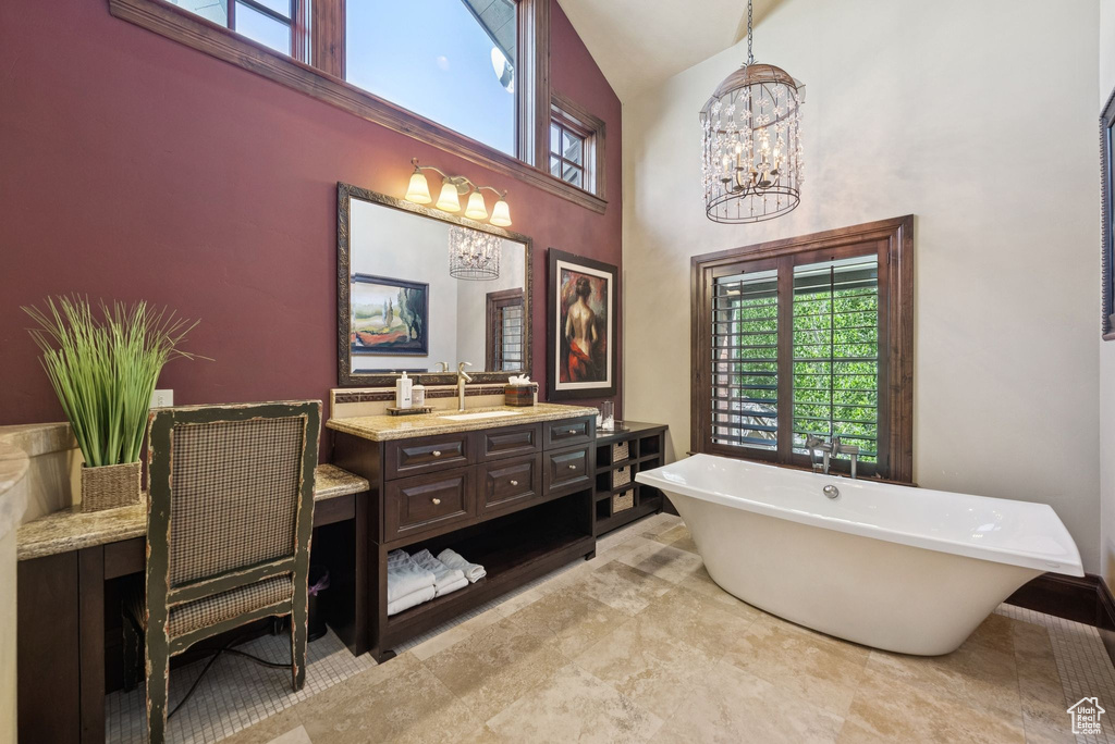 Bathroom featuring a chandelier, high vaulted ceiling, vanity, and a freestanding tub