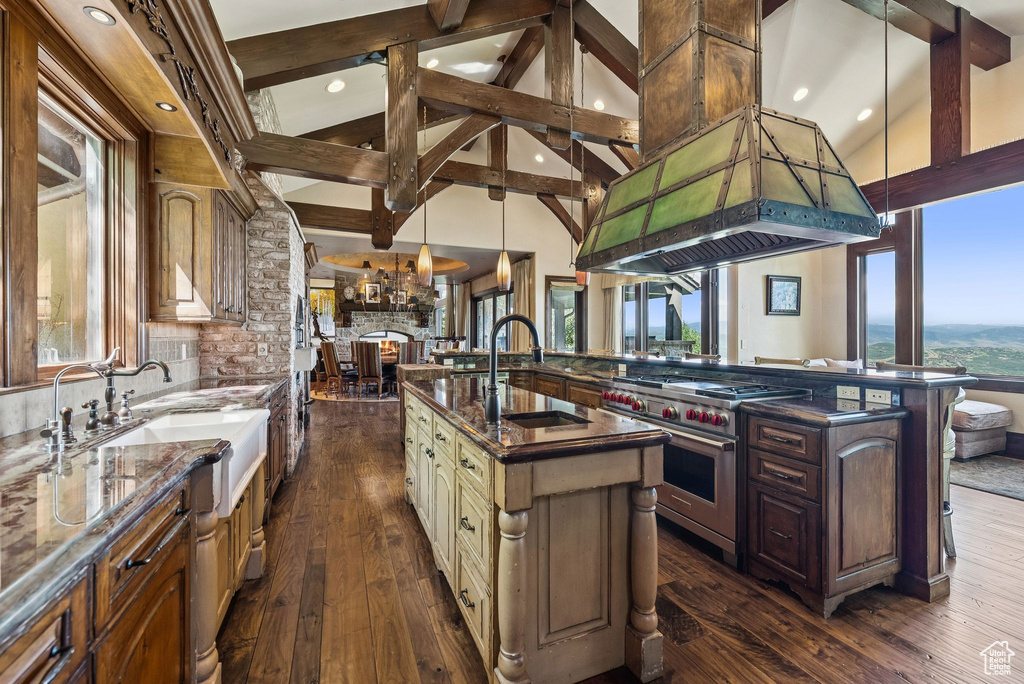Kitchen featuring premium stove, a large island, beamed ceiling, dark wood-style flooring, and dark stone countertops