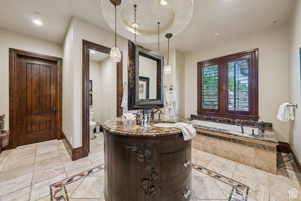 Full bath with a bath, vanity, stone tile flooring, and recessed lighting