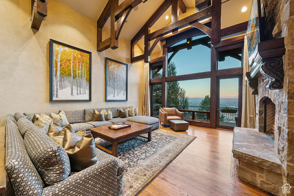 Living room with high vaulted ceiling, beam ceiling, wood finished floors, a fireplace, and a water view