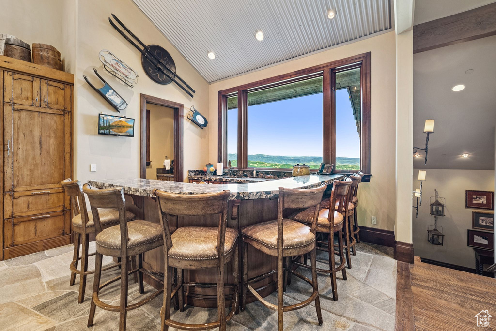 Indoor dry bar with stone tile flooring, lofted ceiling, and recessed lighting