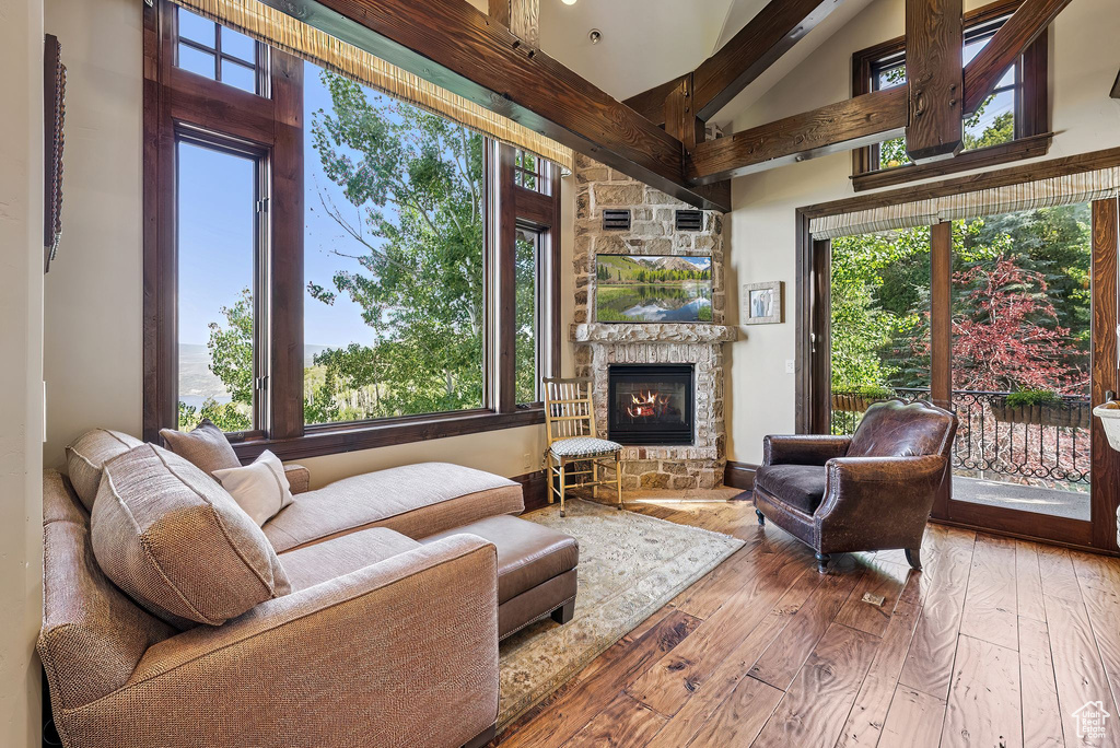 Living room with high vaulted ceiling, wood-type flooring, and a stone fireplace