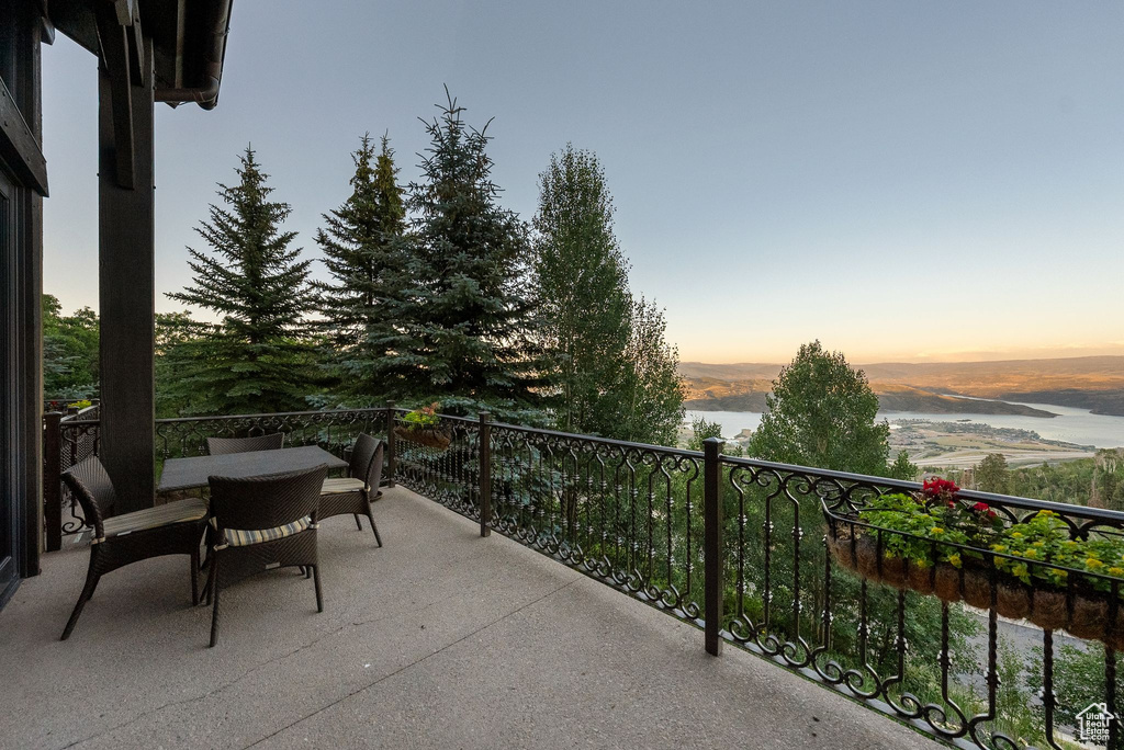 Balcony at dusk featuring a water view and outdoor dining area