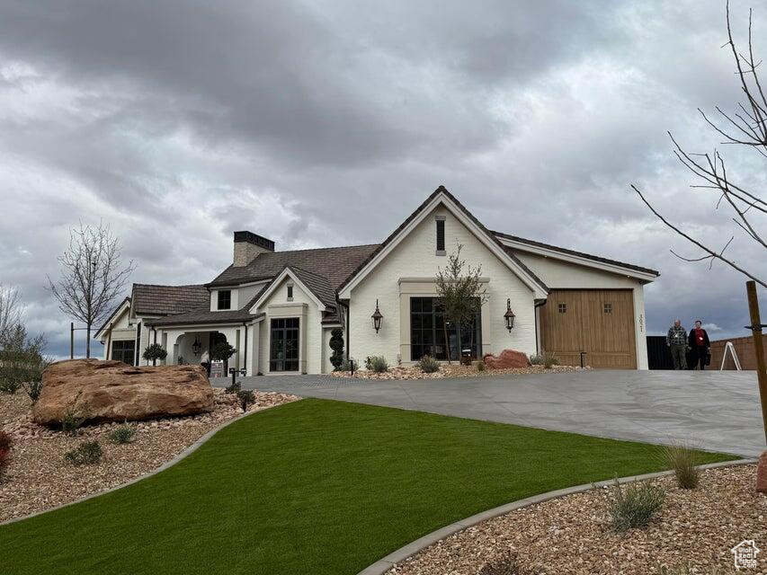 Back of house featuring a yard, a chimney, and concrete driveway