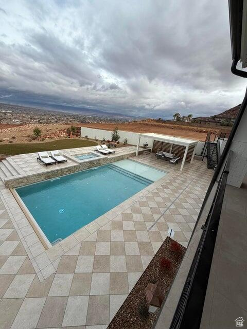 View of pool with an in-ground hot tub and a patio area