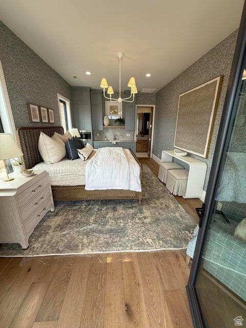 Bedroom with wood finished floors, a chandelier, and recessed lighting