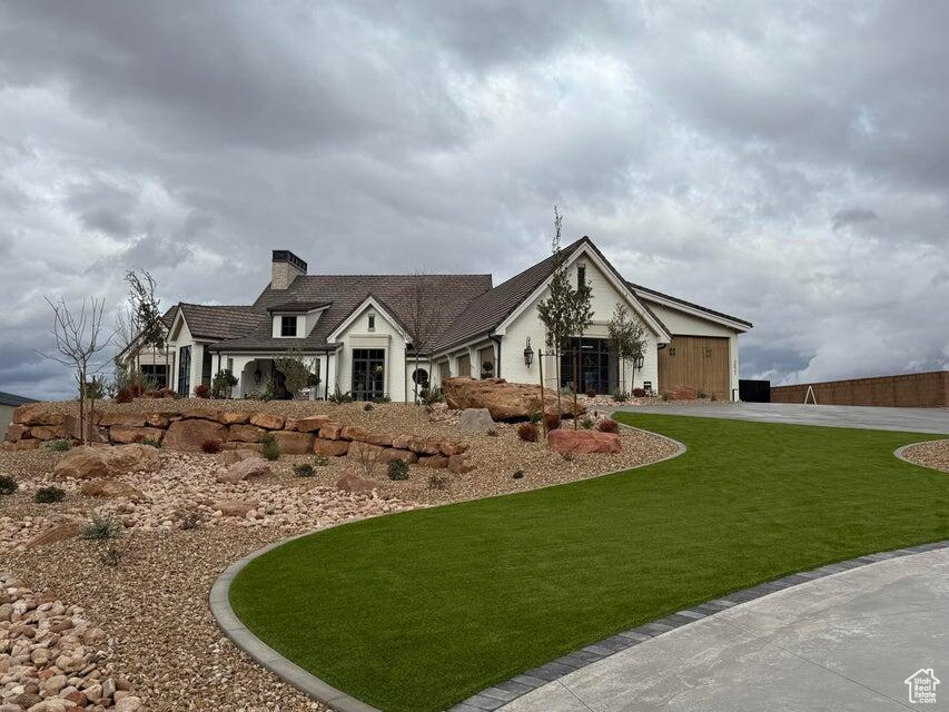 View of front of property featuring a front yard, a chimney, and a garage