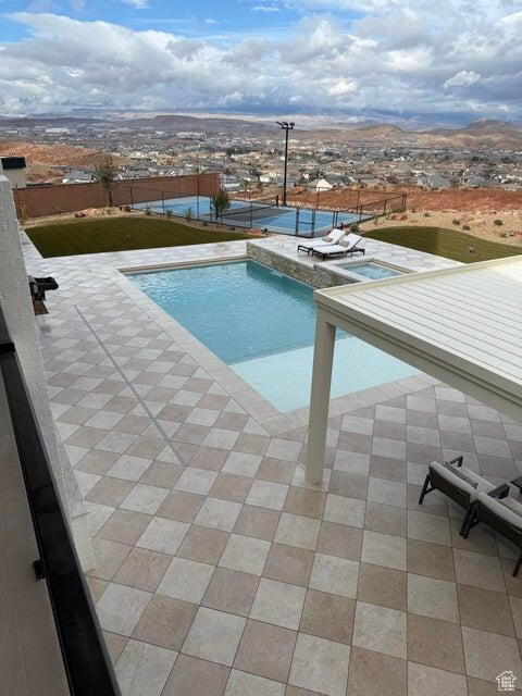 View of swimming pool featuring a patio area, a mountain view, and a jacuzzi