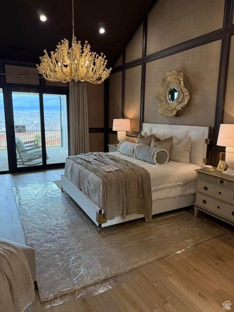 Bedroom with access to outside, wood-type flooring, vaulted ceiling, a chandelier, and recessed lighting