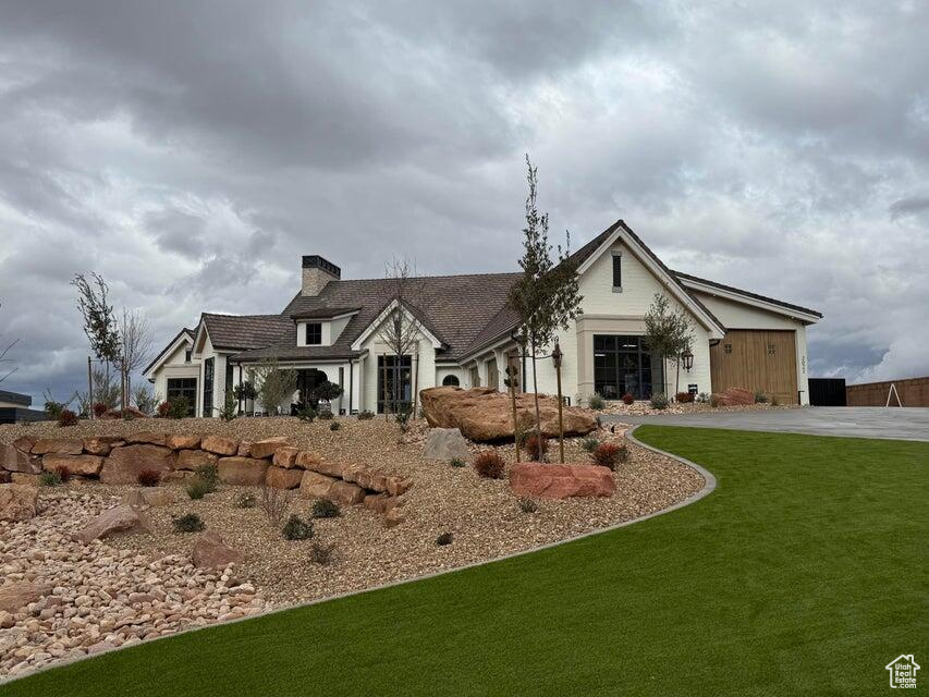 View of front of property featuring a chimney, a front lawn, and driveway