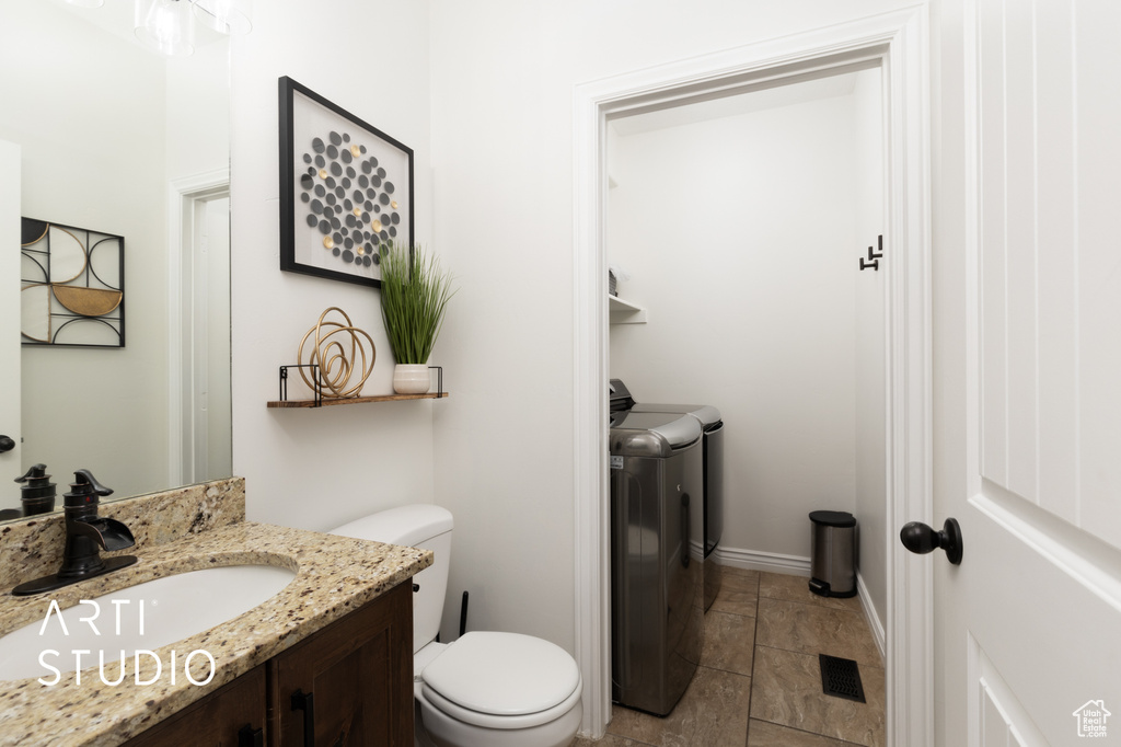 Bathroom featuring washing machine and dryer, vanity, and stone finish floors