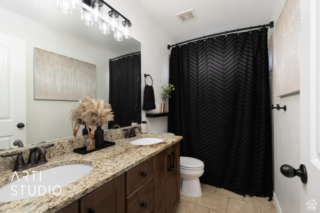 Bathroom with double vanity, tile patterned floors, and a shower with curtain
