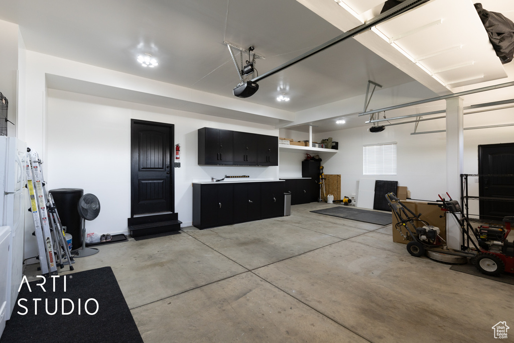 Garage with freestanding refrigerator and a garage door opener