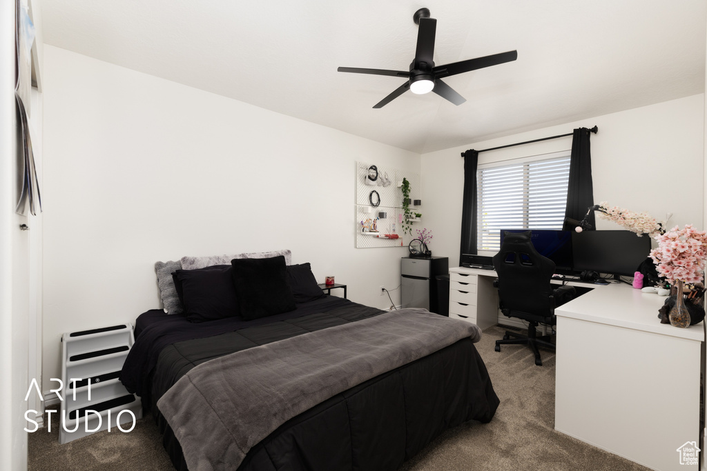 Bedroom with light carpet, an office area, ceiling fan, and fridge