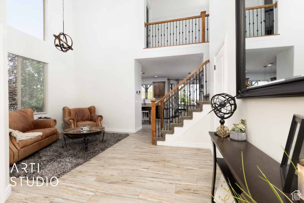 Living area featuring a towering ceiling, stairs, wood finished floors, and a chandelier