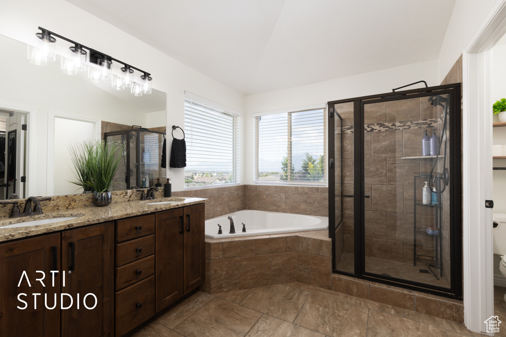 Full bathroom featuring a shower stall, a bath, and double vanity