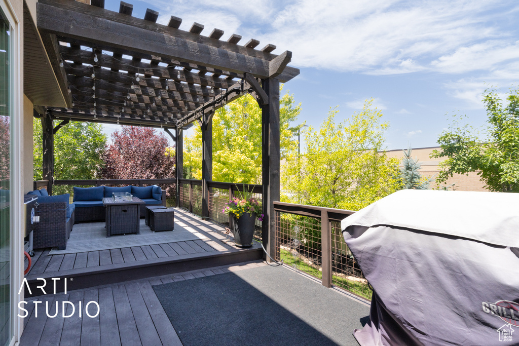 Wooden deck with an outdoor hangout area, a pergola, and a grill