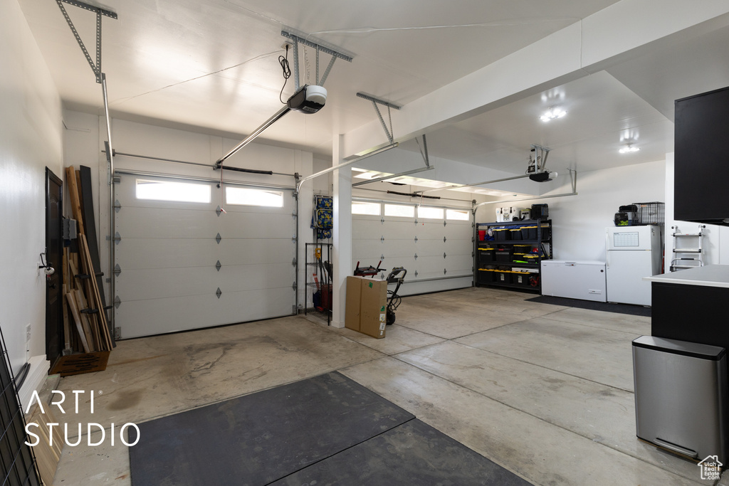 Garage with freestanding refrigerator and a garage door opener
