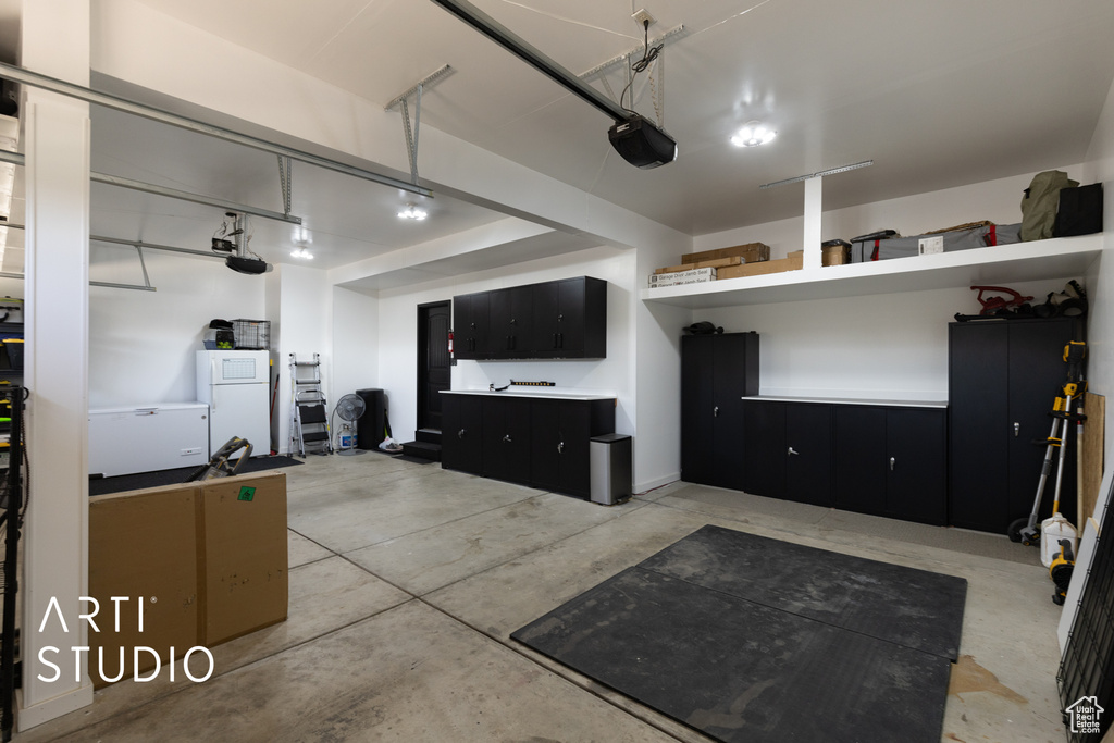 Garage featuring freestanding refrigerator and a garage door opener