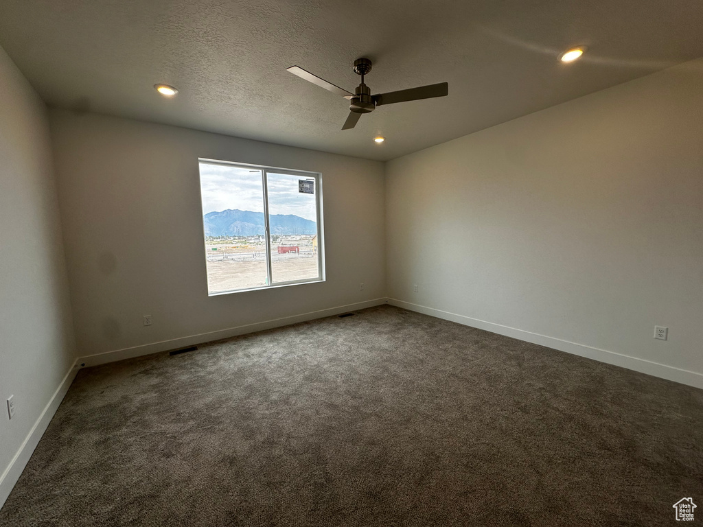 Empty room with dark carpet, ceiling fan, and recessed lighting