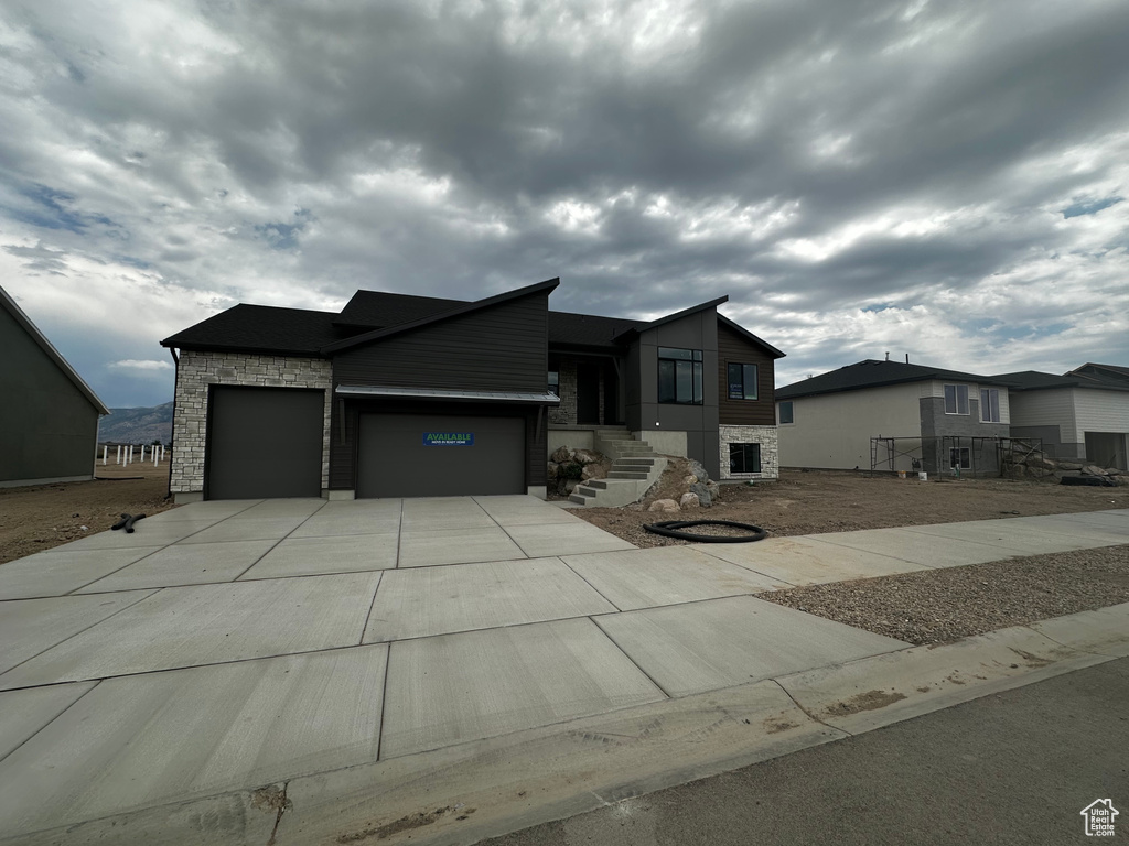 View of front facade with stone siding, a garage, and driveway