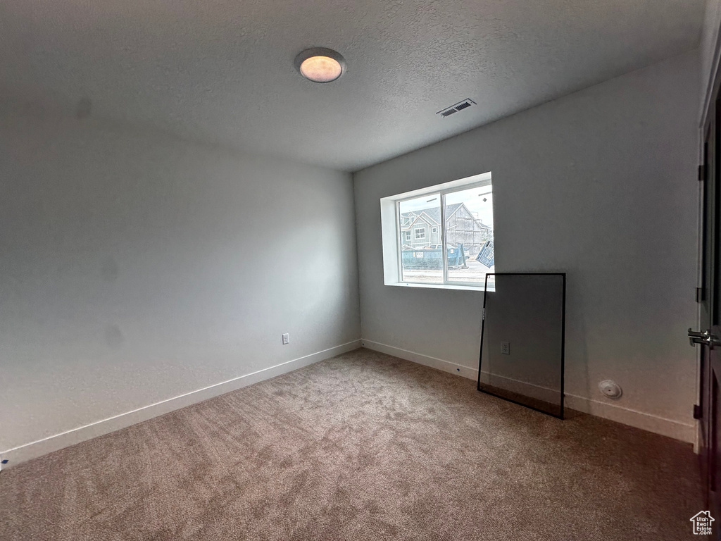 Carpeted empty room featuring baseboards and a textured ceiling