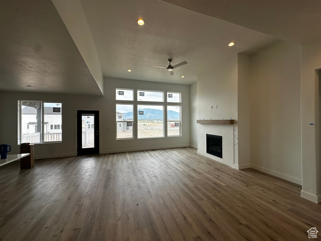 Unfurnished living room with plenty of natural light, wood finished floors, a fireplace, and recessed lighting