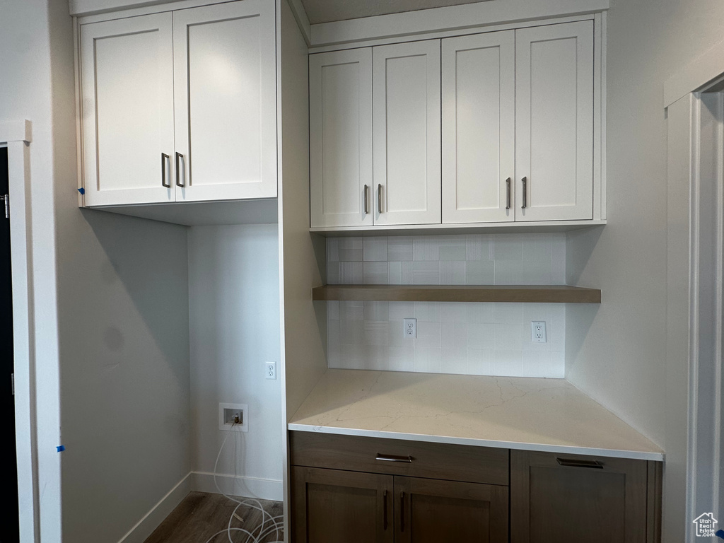 Kitchen with open shelves, backsplash, light stone countertops, dark wood-style floors, and white cabinets