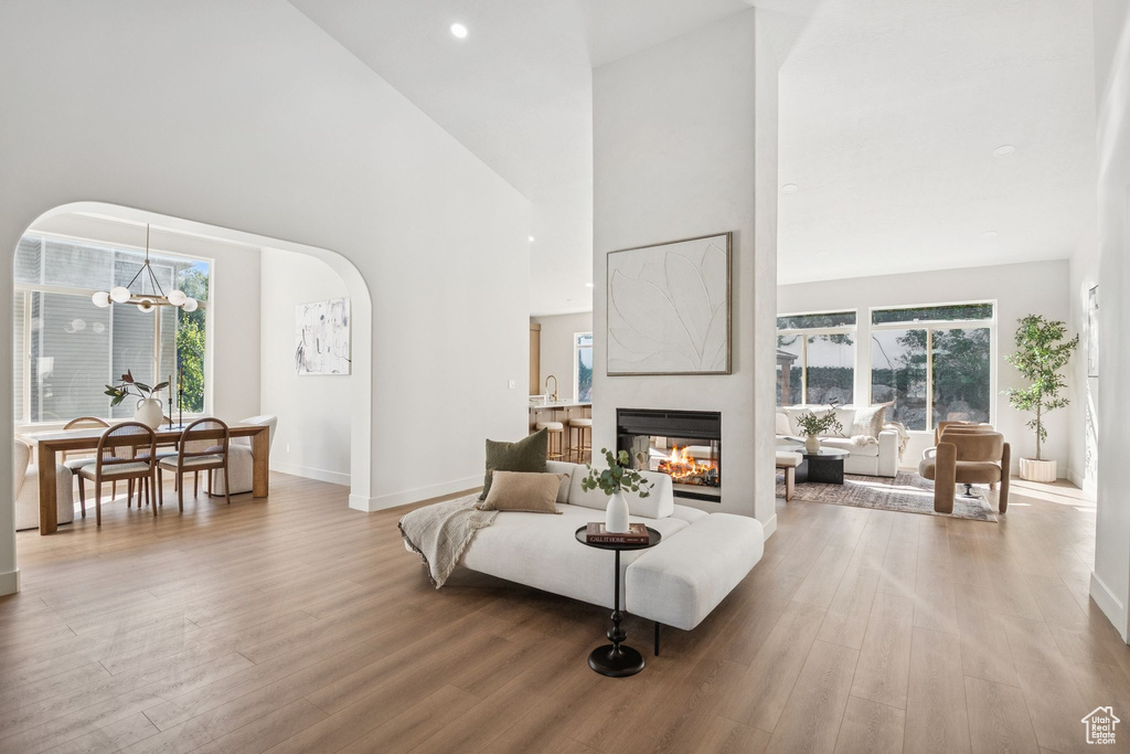 Living area featuring arched walkways, a high ceiling, wood finished floors, and a chandelier