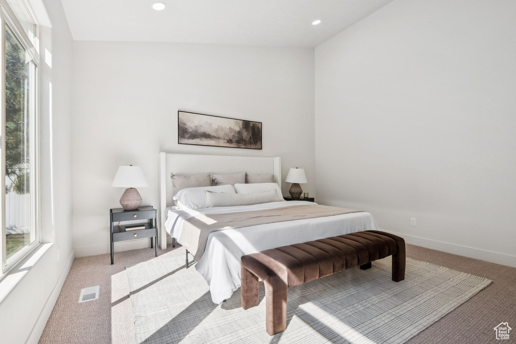 Bedroom featuring light colored carpet, multiple windows, and recessed lighting