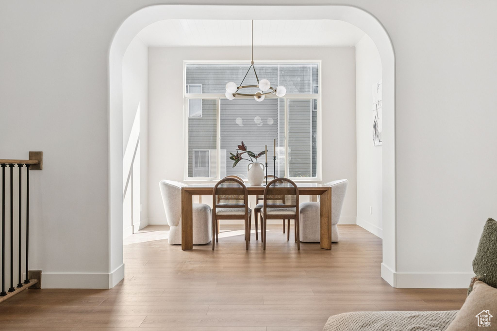 Dining room featuring arched walkways, a chandelier, light wood-type flooring, and radiator