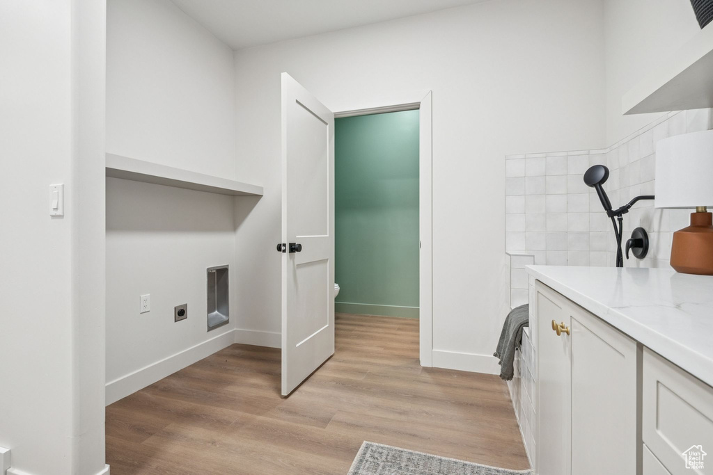 Laundry area with light wood-type flooring and baseboards