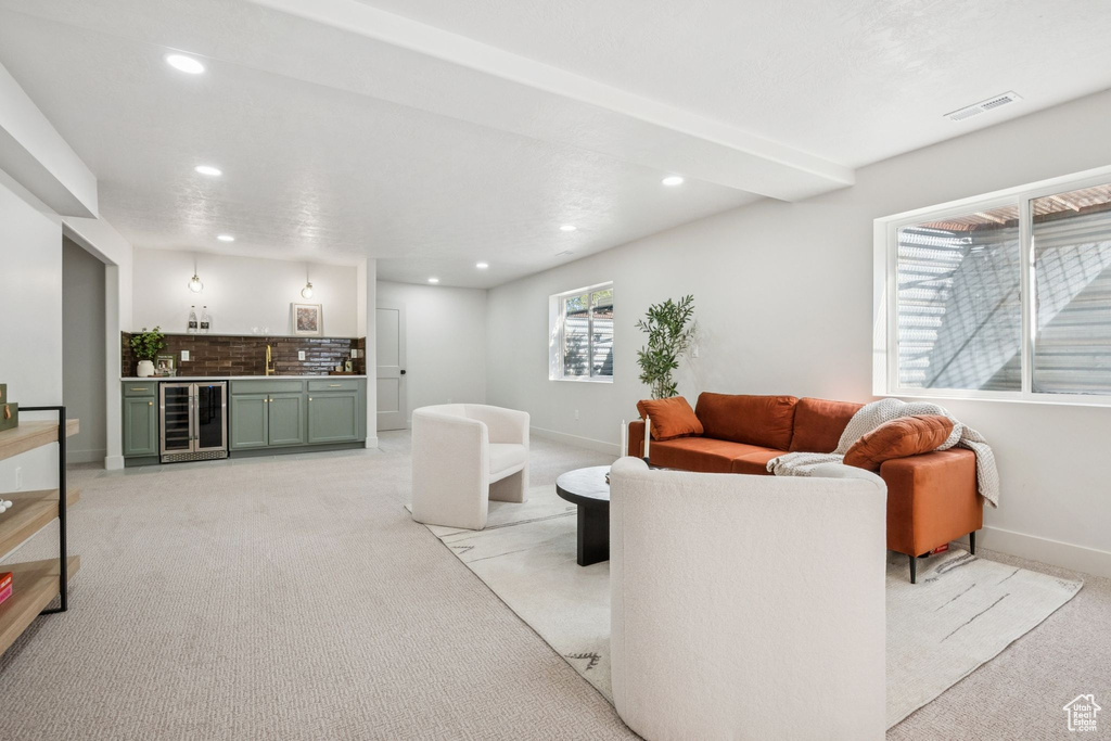 Living area featuring bar with sink, light carpet, recessed lighting, and wine cooler