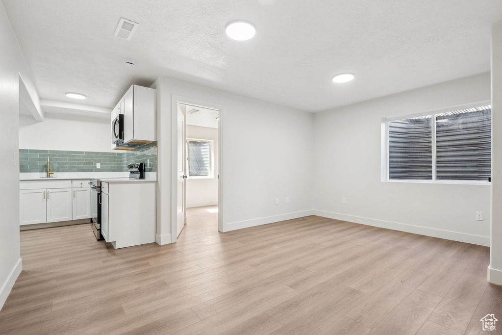 Kitchen featuring light countertops, light wood-style floors, range, white cabinets, and recessed lighting
