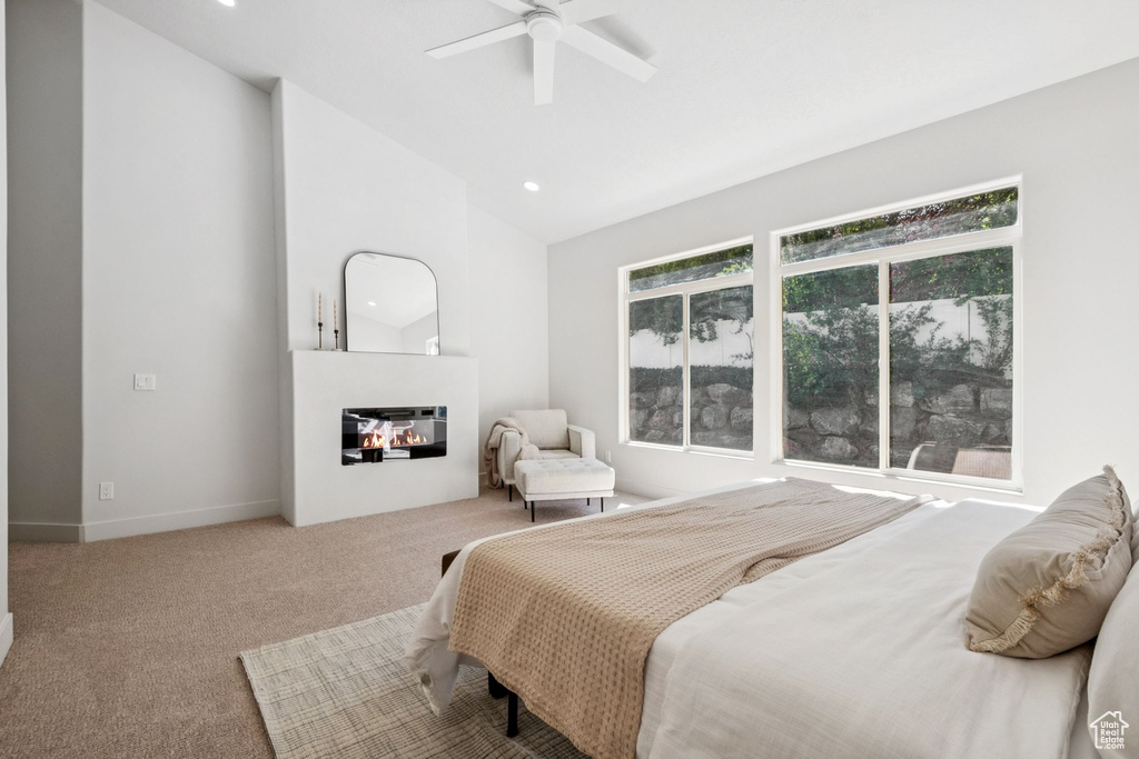 Bedroom featuring vaulted ceiling, a glass covered fireplace, carpet, recessed lighting, and a ceiling fan