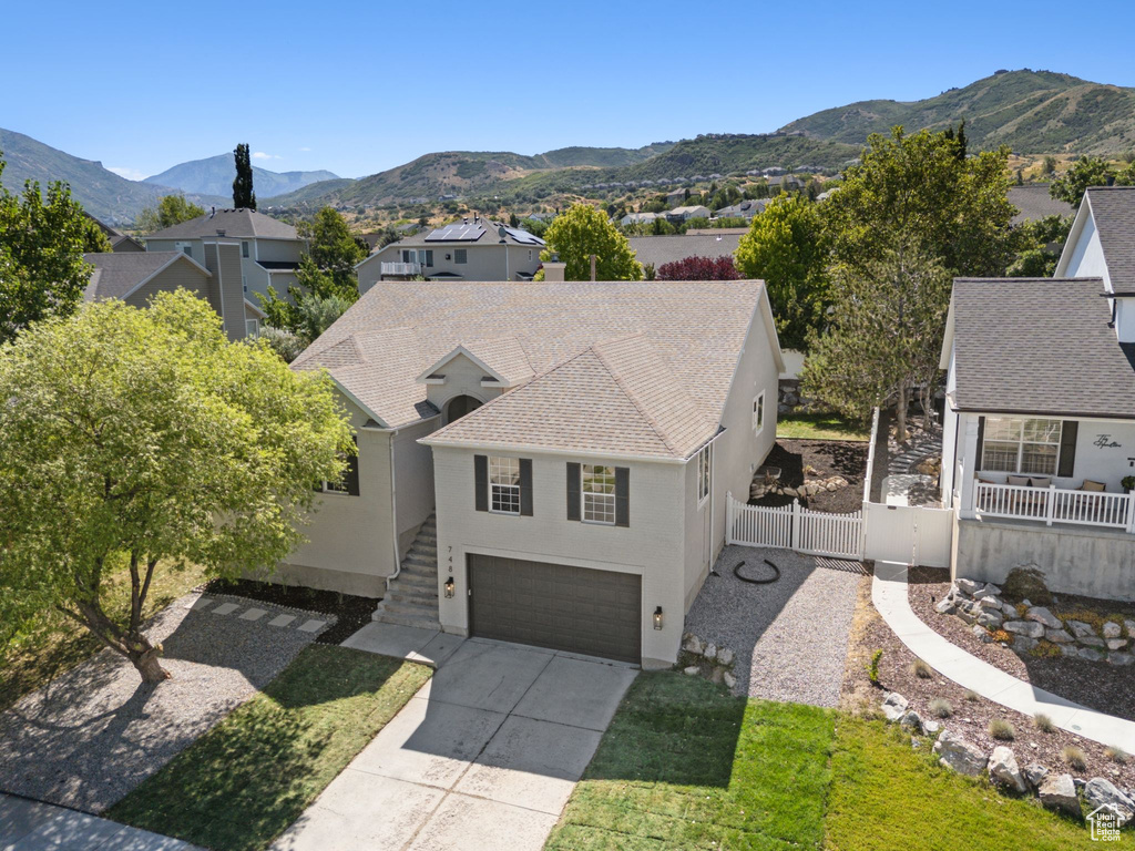View of front of house with stucco siding, a shingled roof, driveway, a garage, and a mountain view